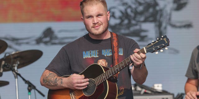 Zach Bryan plays guitar on stage