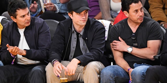 Robert Pattinson in a black baseball hat at Lakers game