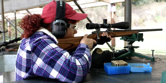 Woman looks through scope on a bolt-action rifle at a gun range near Tacoma, Washington