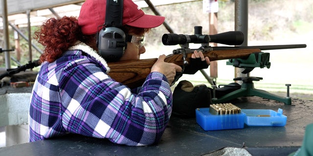 Woman looks through scope on a bolt-action rifle at a gun range near Tacoma, Washington