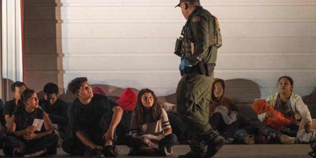 Migrants wait for a bus to take them to a processing center after they turned themselves over to US Border Patrol agents