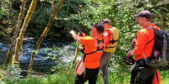 searchers on Clackamas River shore