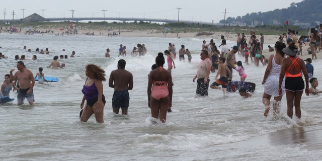 People swim in the Atlantic Ocean on a beach at Sandy Hook