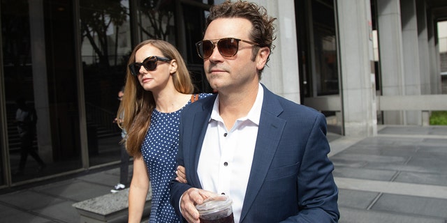 Danny Masterson holds a cup of coffee while walking into courthouse with wife Bijou Phillips