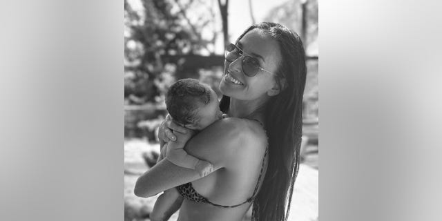 A photo of Demi Moore wearing a leopard print bikini and holding her newborn granddaughter.