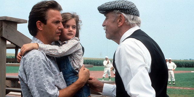 Kevin Costner and Gabby Hoffman stand in front of baseball diamond in a Field of Dreams scene