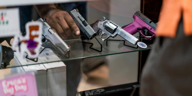 customer looks at guns in display case