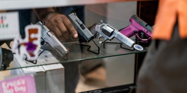 customer looks at guns in display case