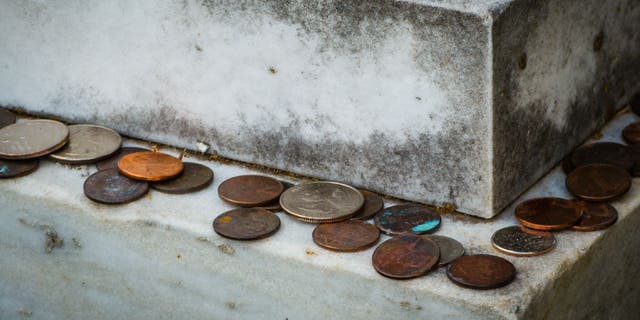 Coins left on the edge of a headstone