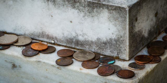 Coins left on the edge of a headstone