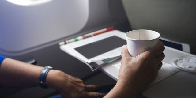 Airplane passenger uses tray hold cup