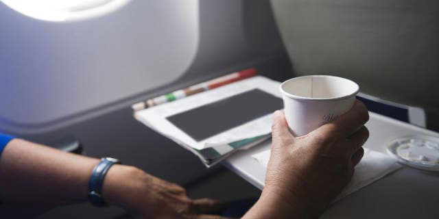 Airplane passenger uses tray hold cup