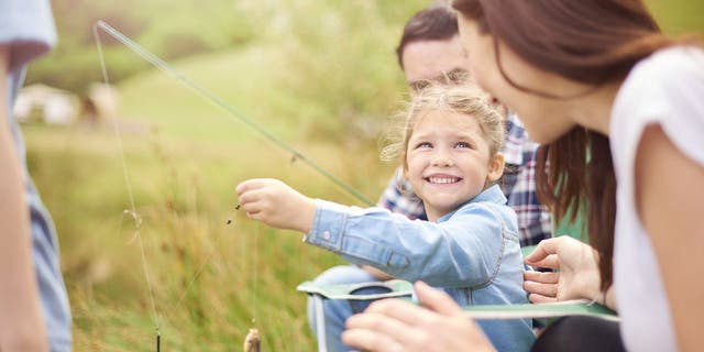 Family goes fishing at a lake.