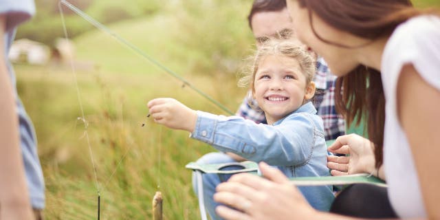 Family goes fishing at a lake.