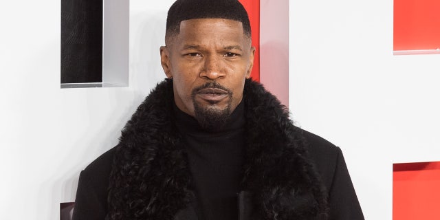 Jamie Foxx wears a black coat with a furry neckline at a movie premiere