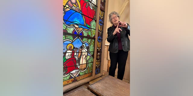 professor standing by stained glass panel