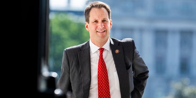 Rep. JIm Himes walks into the Capitol Building wearing a suit and red tie 