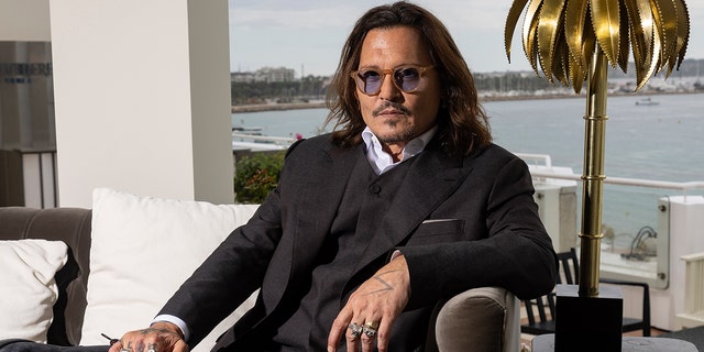 Johnny Depp wears suit with purple shirt during interview in France