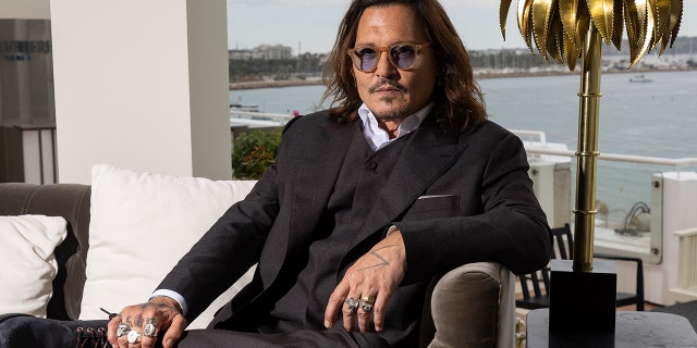 Johnny Depp wears suit with purple shirt during interview in France