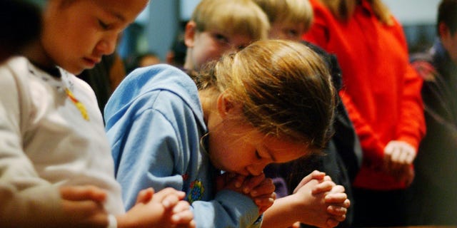 Susan (no last names released) bows her head in prayer as she and fellow fourth-grader Carolyne (L) attend a prayer service to give thanks that no one has died since a car plowed into 12 children, including Vanessa, and three teachers the day before at Westminster Academy Christian Day School, Jan. 31, 2002, in Eagle Rock near Los Angeles, Calif.