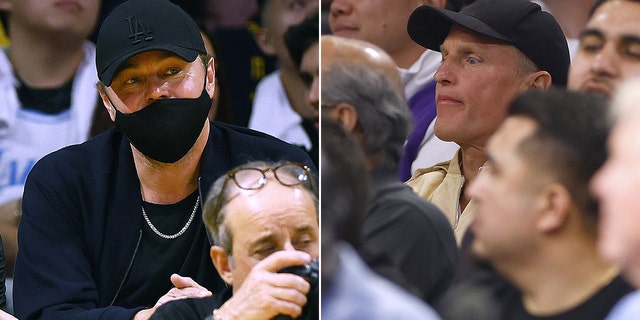 Leonardo DiCaprio sits behind a cameraman wearing a black baseball cap and face mask watching the Lakers split Woody Harrelson in the crowd wearing a black baseball cap and tan shirt