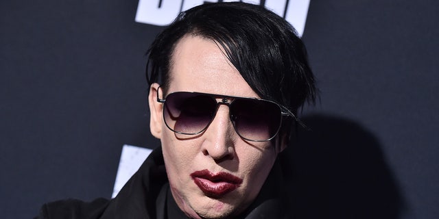 Marilyn Manson wears dark sunglasses and maroon lipstick at red carpet event