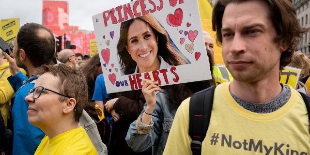 A protesters holding a sign calling Meghan the "princess of hearts"