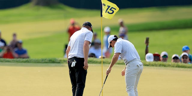 Michael Block and Rory McIlroy look at hole