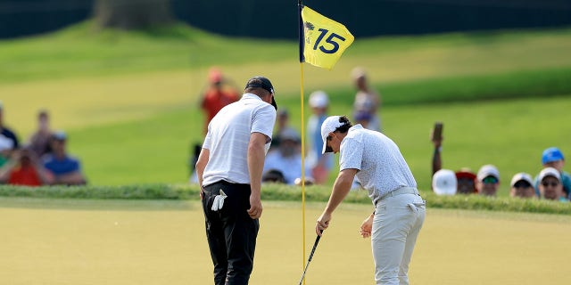 Michael Block and Rory McIlroy look at hole