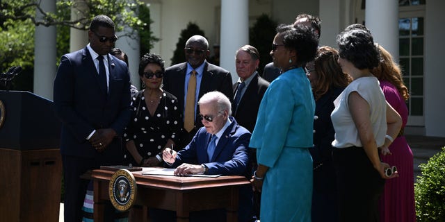 US President Joe Biden (C) signs an executive order on new actions to advance environmental justice