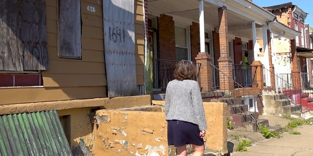 Councilwoman walks in front of boarded up homes in Baltimore, Maryland