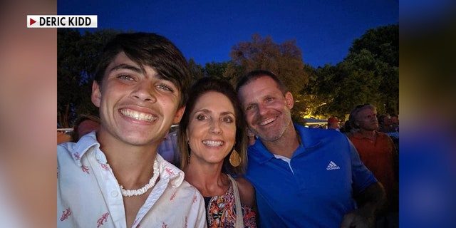 A young teen smiles with his parents in a selfie