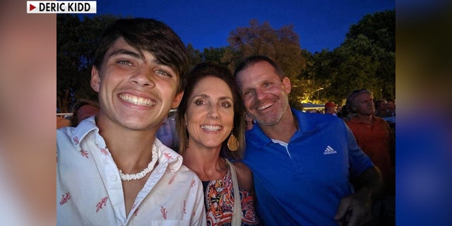 A young teen smiles with his parents in a selfie