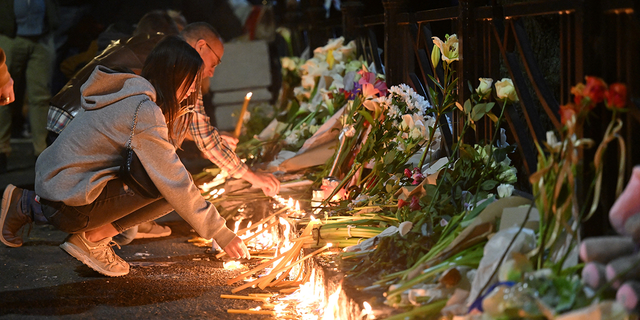 Students lay out candles on a memorial