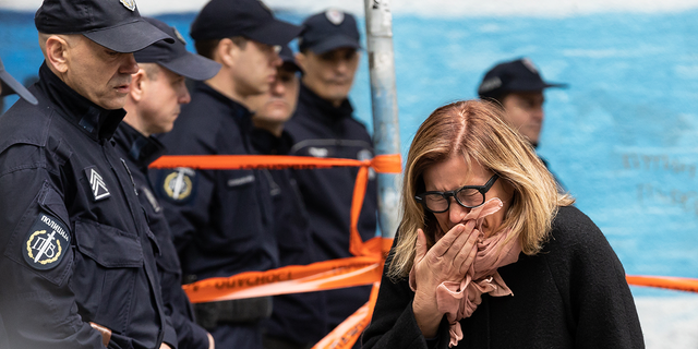 Serbian woman cries into scarf in front of police line