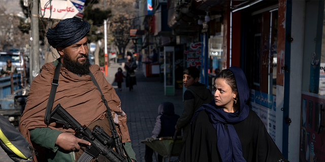Combatiente talibán y una mujer afgana