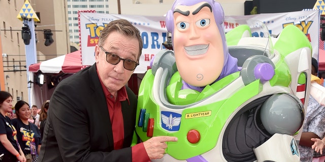 Tim Allen posing with a life size Buzz Lightyear at premiere of Toy Story 4