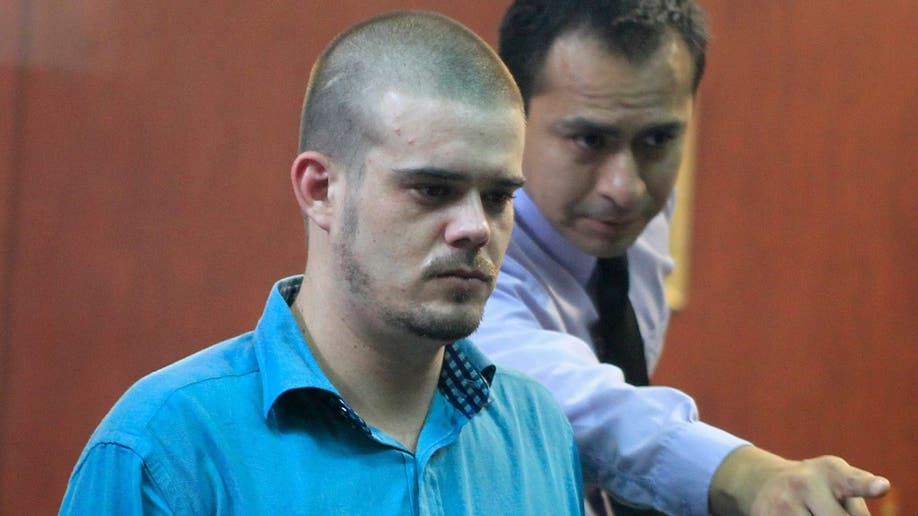 A man directs Dutch citizen Joran Van der Sloot to his seat before the trial in the Lurigancho prison in Lima