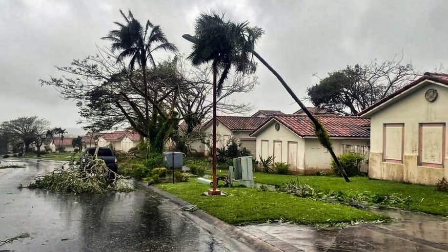 Downed tree branches litter a neighborhood in Yona, Guam