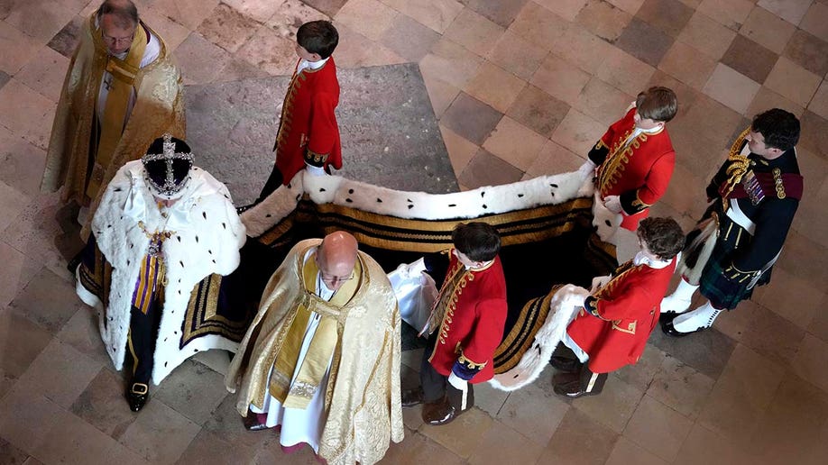 King Charles III, accompanied by his pages, walks in the Coronation Procession after his coronation ceremony at Westminster Abbey. 