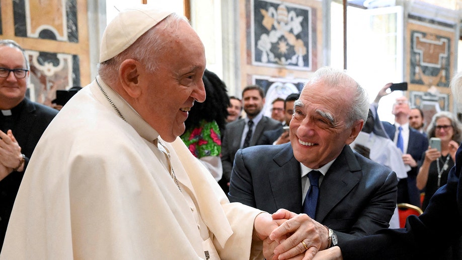 Martin Scorsese holds onto Pope Francis' hand at the Vatican and smiles big