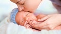 Close up of sleeping newborn and kissing mother