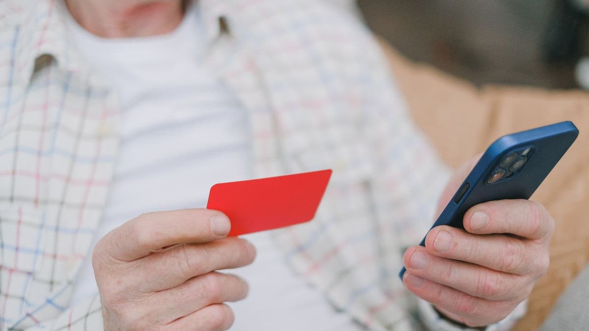 Man holds credit card and his phone