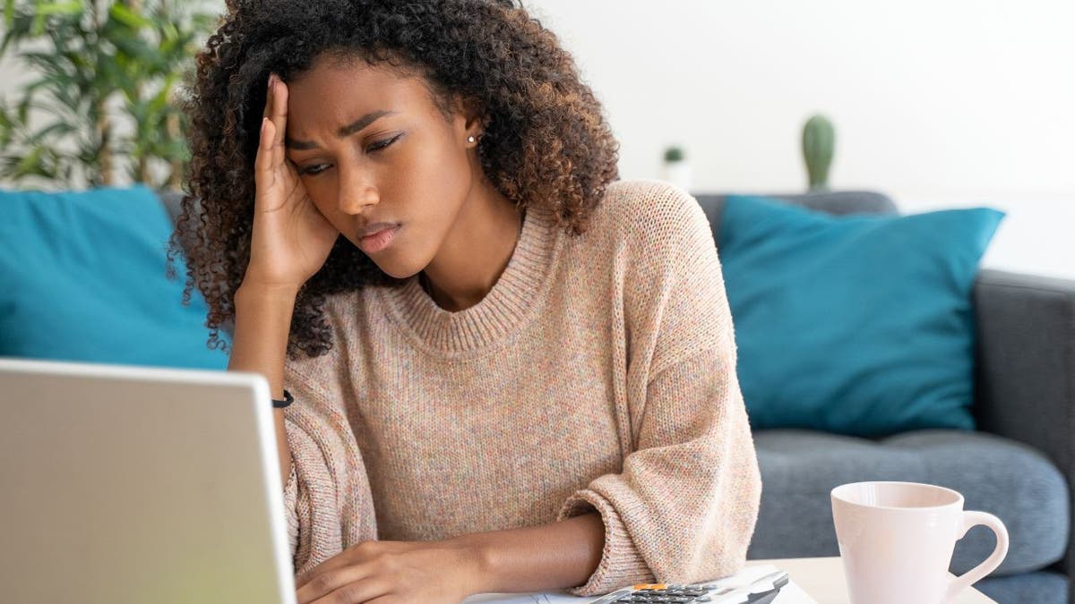 Woman visibly upset, staring at her laptop.