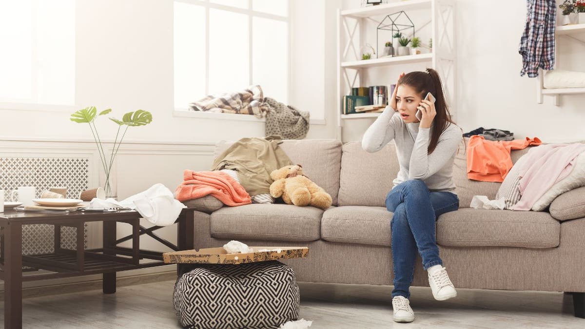 Girl looking nervous while sitting on couch while on the phone 