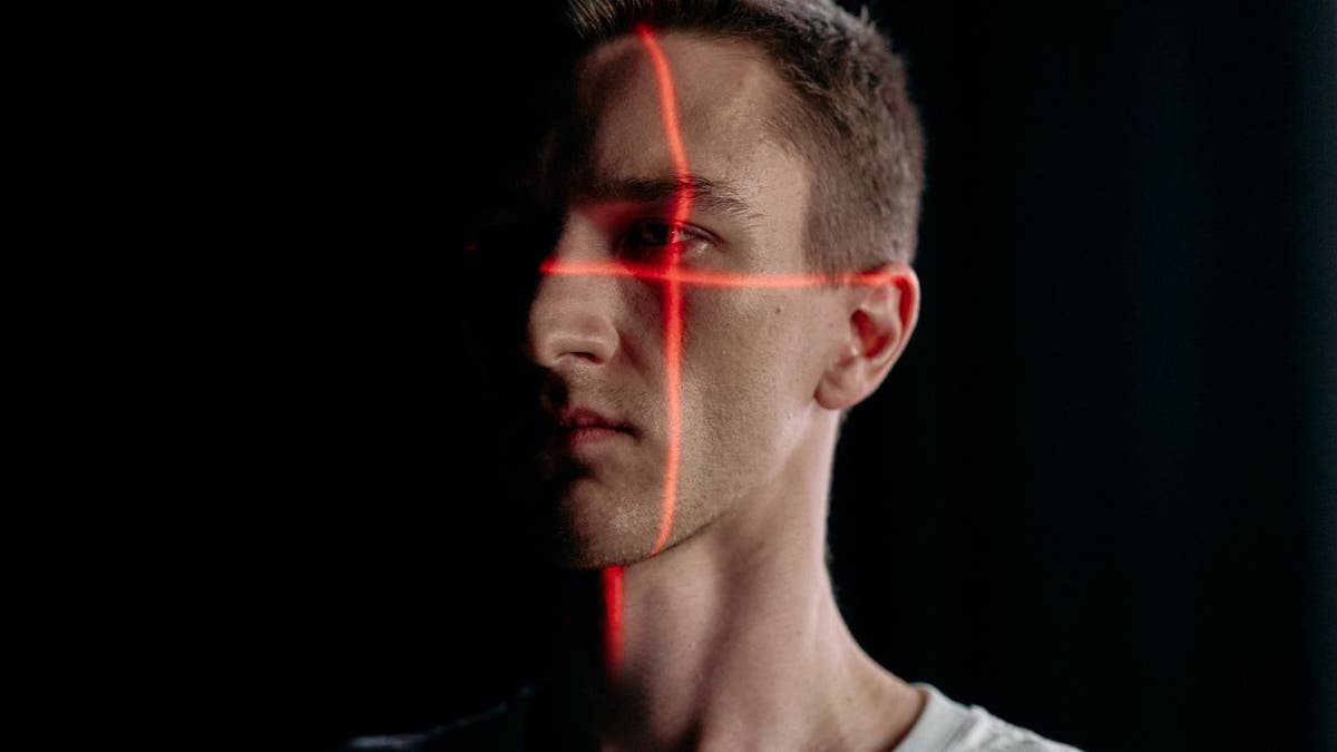 Photo of a man's face being scanned by two red lines.