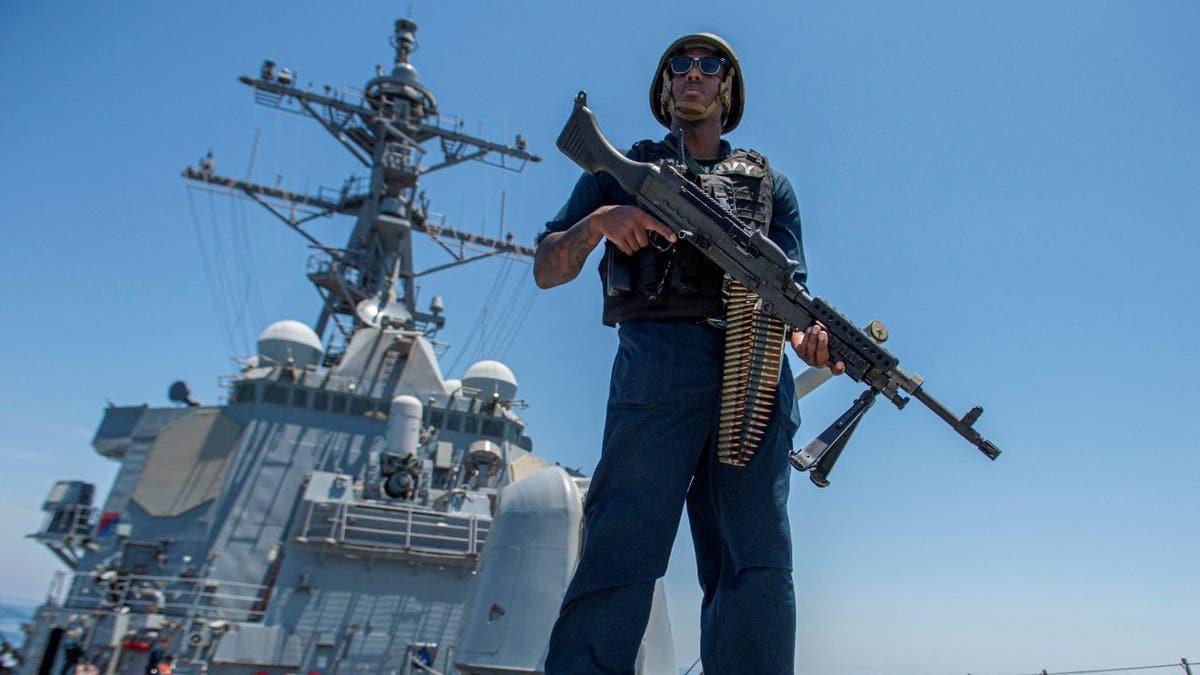 US Navy sailor on deck with rifle