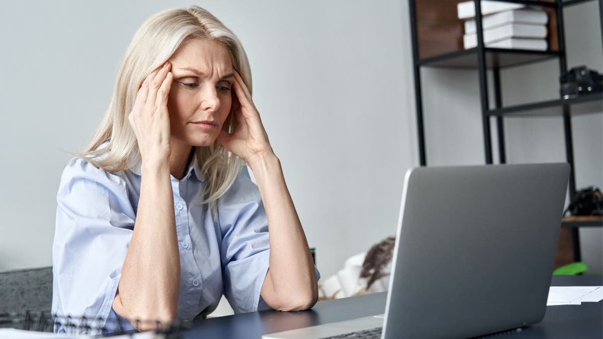 A picture of a woman stressed on her laptop
