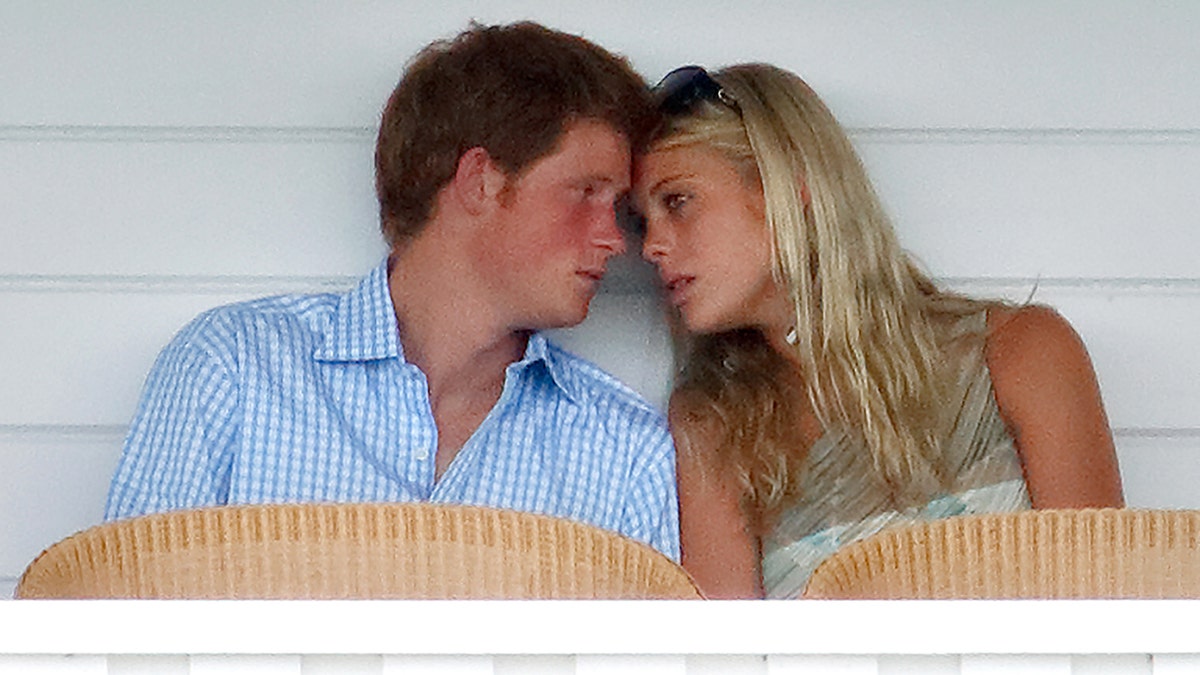 Prince Harry in a blue and white striped shirt leaning againsyt Chelsy Davy in a green and white top