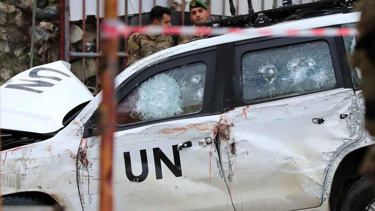  Lebanese soldiers look at a destroyed car